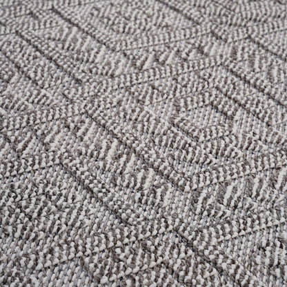 Close-up of the Guros - Traditional Indoor / Outdoor Area Rug, featuring a textured woven fabric with a geometric diamond pattern in shades of gray and off-white. Raised threads add a soft, three-dimensional effect to the surface.