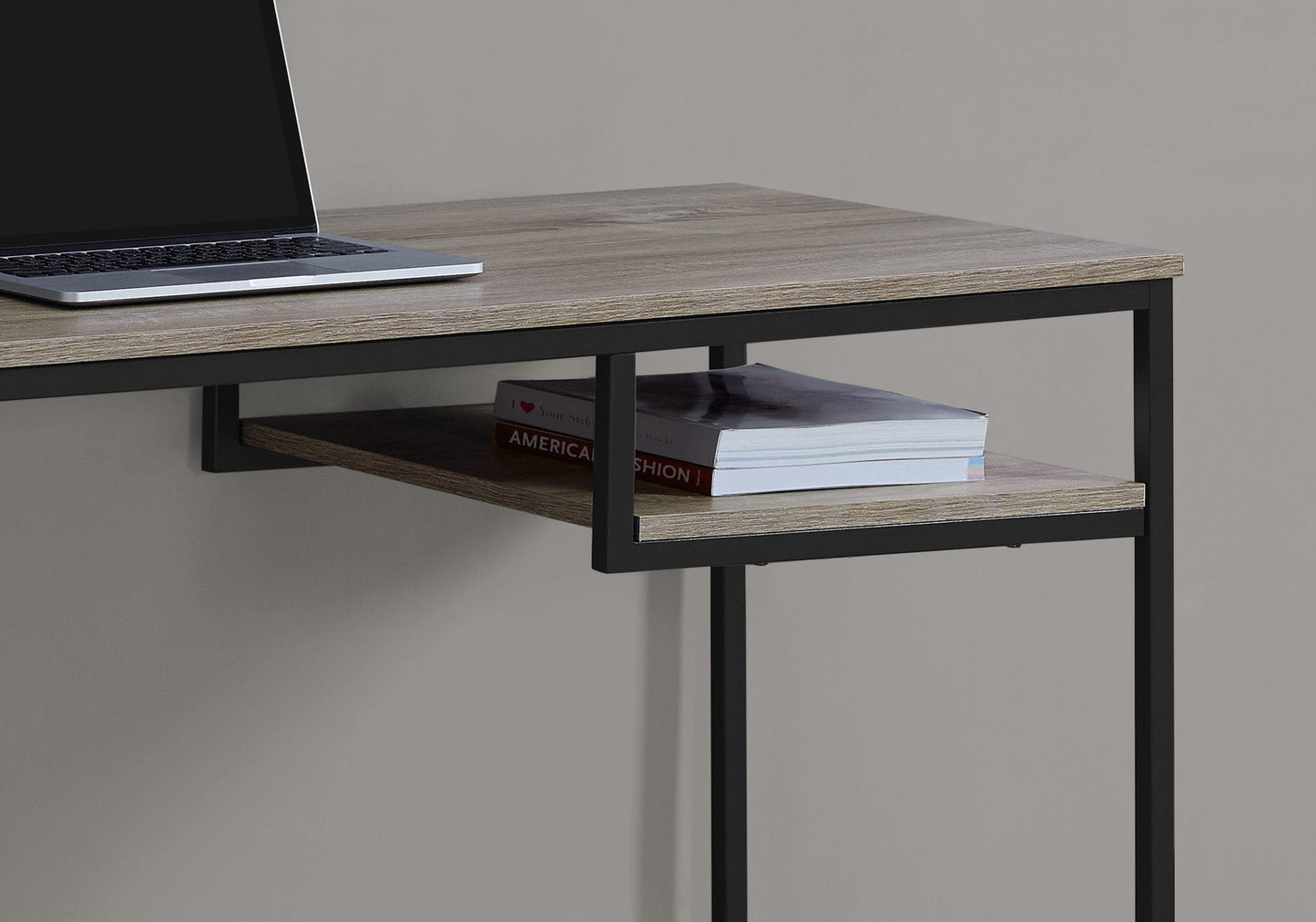 A close-up of the Computer Desk For Home Office, Compact Modern Design, showcasing its wooden surface, black metal frame, open shelf with two books beneath the desktop, and a laptop partially visible on top.