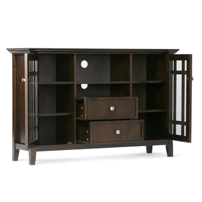 The Bedford - Handcrafted Tall TV Media Stand features dark wood, glass-paneled doors that open to reveal shelves, two central drawers, cable holes in the back panel, and stands on short legs.