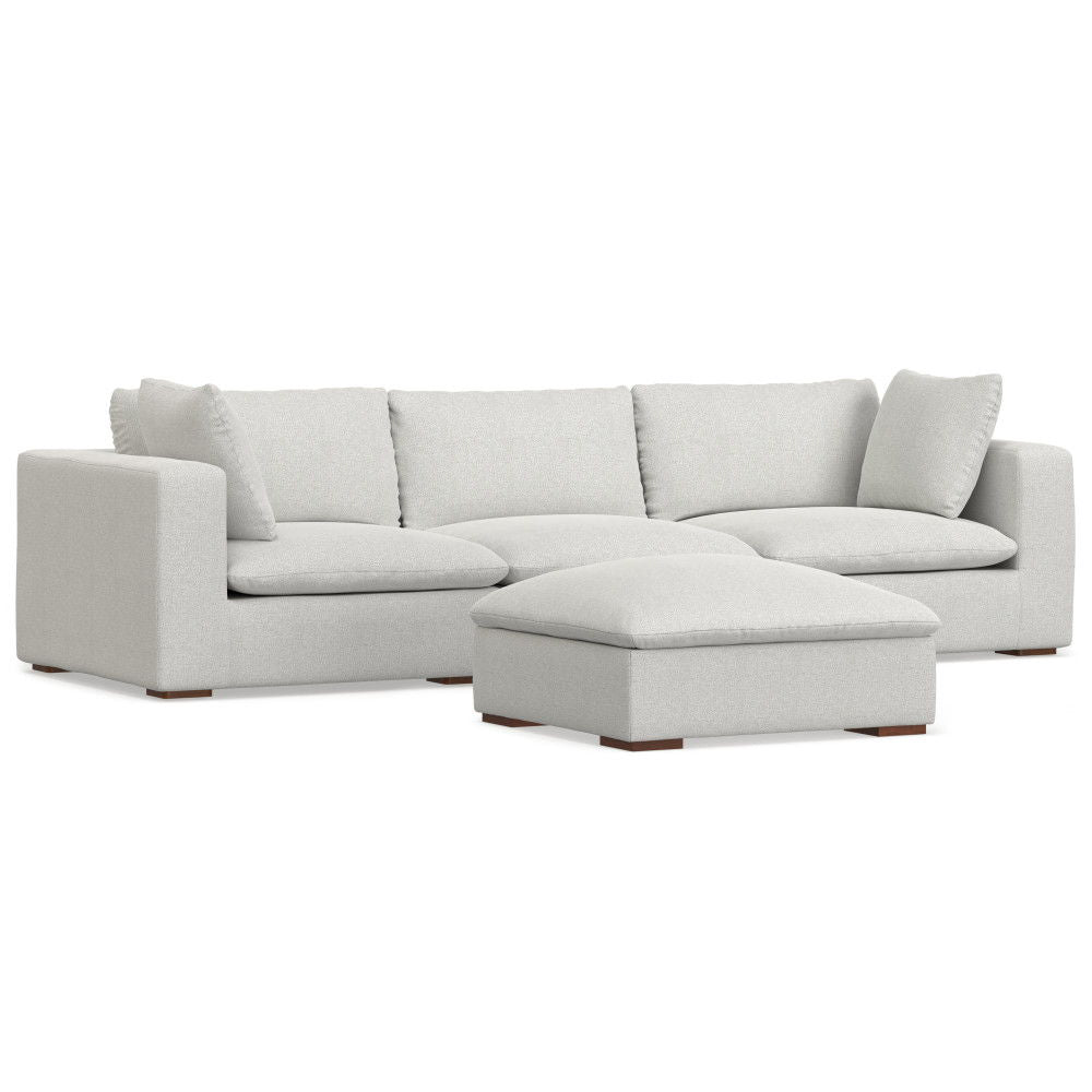 The Jasmine - Handcrafted Sofa And Ottoman features a modern light gray sectional with three seat cushions, three back cushions, two matching pillows, and a large rectangular ottoman, shown against a white background.