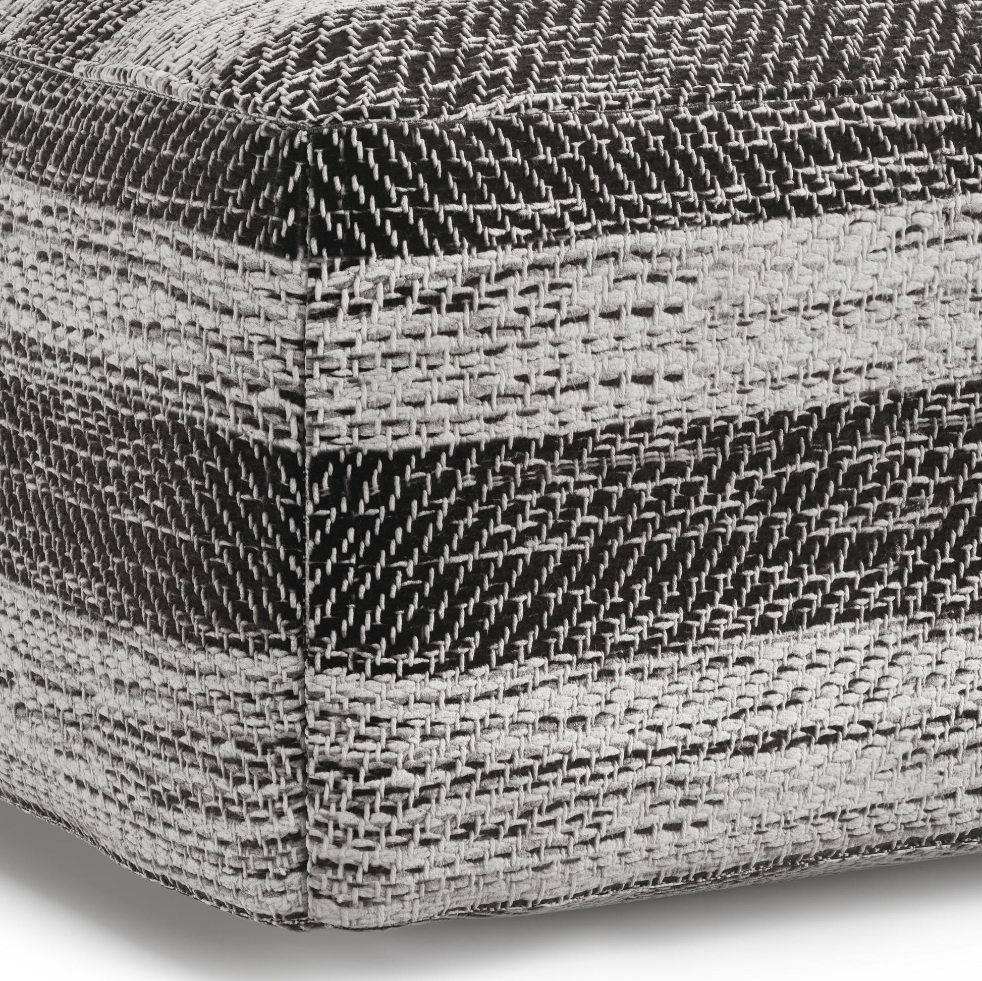 Close-up of the Clay - Square Pouf, Upholstered, showing a coarse woven fabric with horizontal black, white, and gray textured stripes and a visible corner seam.