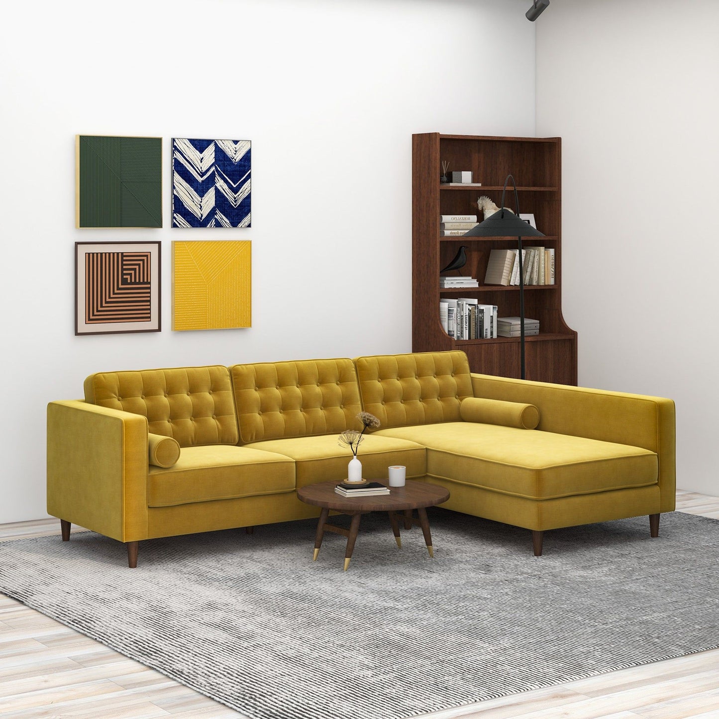 A modern living room featuring the Christian Mid-Century Modern Design Sectional Sofa in yellow, a round wooden coffee table, gray rug, wooden bookshelf with books and decor, and four colorful abstract art pieces on a white wall.