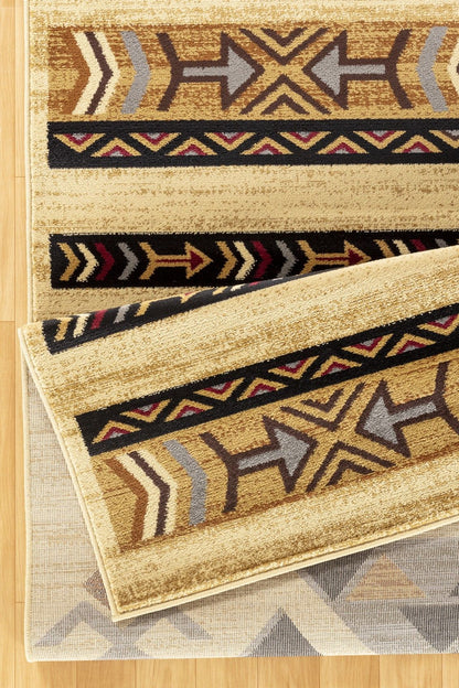 A close-up of two overlapping Tribes - GC_YLS4006 Southwest Area Rugs featuring geometric arrow patterns in brown, yellow, black, red, and gray on a light wood floor.