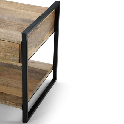 A close-up of the Riverside - Table, a modern wooden side table featuring an open black metal frame, one drawer, and a lower shelf, set against a white background.