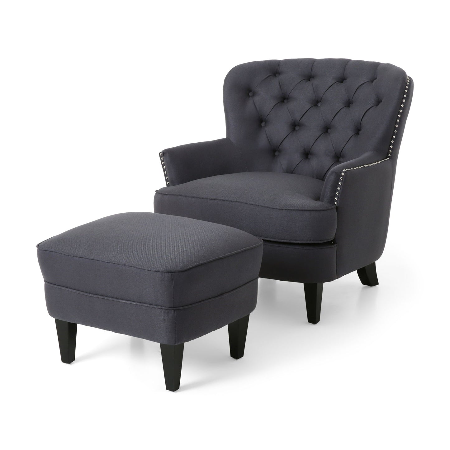 The Enchante Living Room Set features a dark gray tufted-back club chair with silver nailhead trim and dark wooden legs, paired with a matching rectangular ottoman, both displayed against a white background.