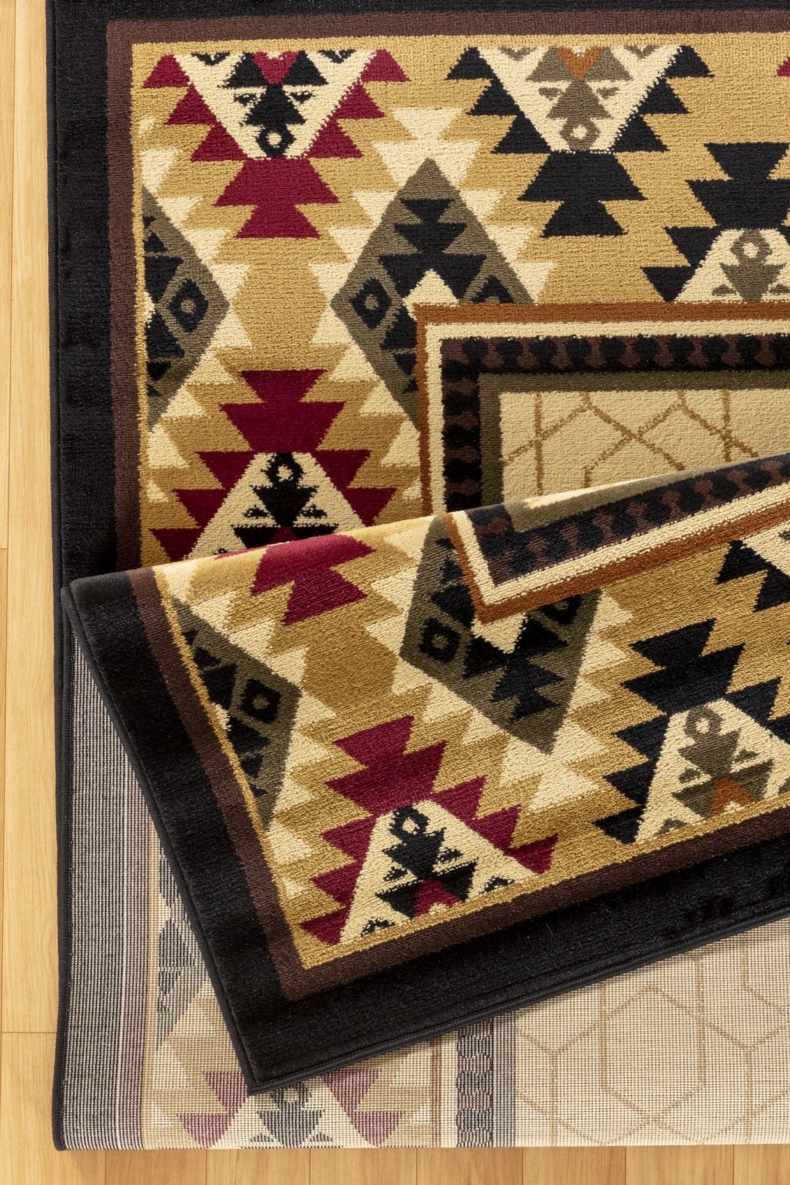 A close-up of the Tribes - GC_YLS4007 Southwest Area Rug, showing bold geometric patterns in red, cream, black, and tan with triangles and diamond shapes and thick borders on a light wood floor.