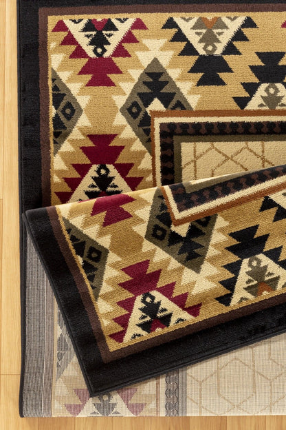 A close-up of the Tribes - GC_YLS4007 Southwest Area Rug, showing bold geometric patterns in red, cream, black, and tan with triangles and diamond shapes and thick borders on a light wood floor.