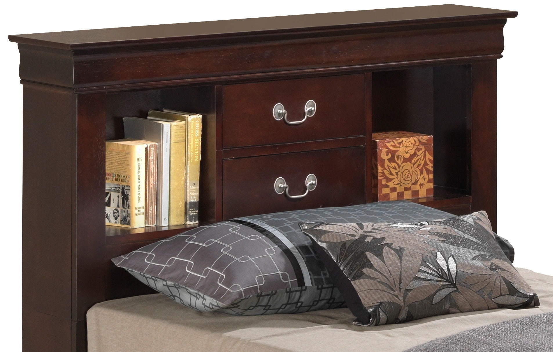 The Louis Phillipe Bookcase Storage Bed features a dark wood headboard with two silver-handled drawers and open shelves that display books and a decorative box, paired with patterned gray and black pillows and a beige sheet.