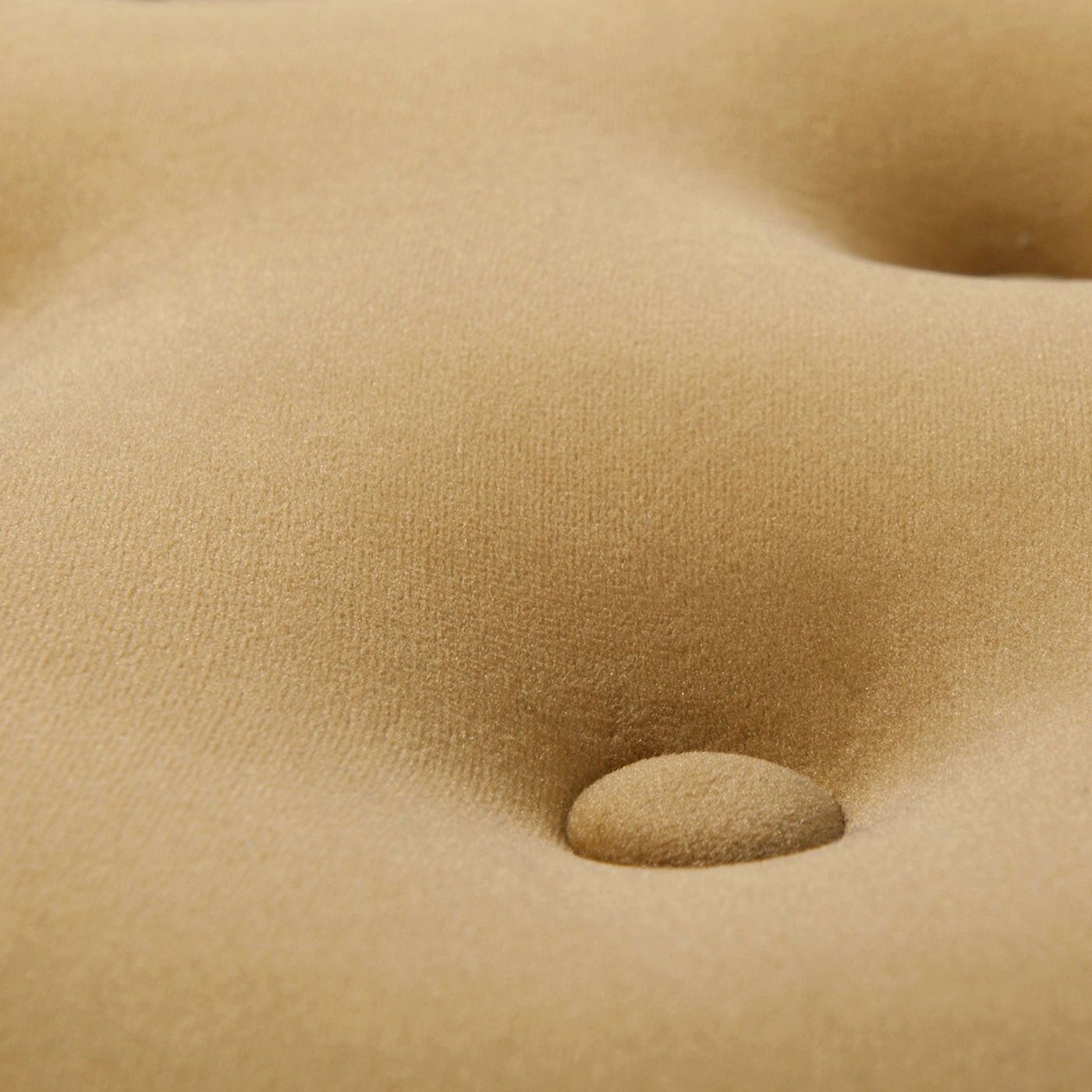 Close-up of the Yolanda Luxurious Upholstery Round Ottoman, featuring a tan, soft velvety surface with button-tufted detailing like an elegant cushion.