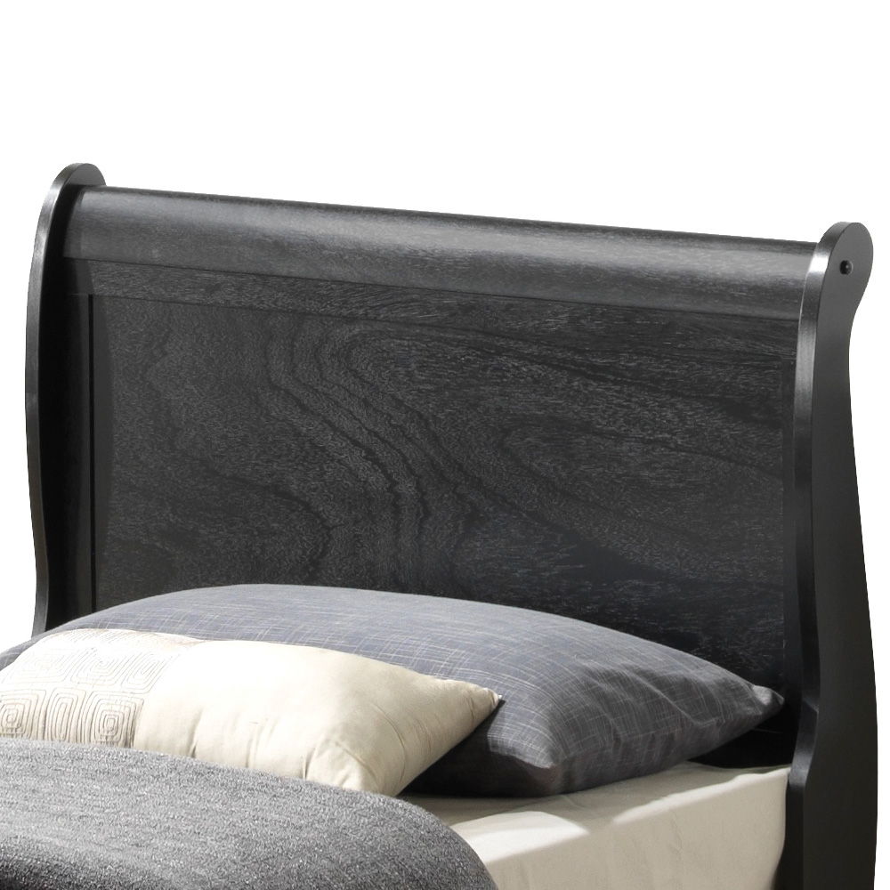 A close-up of the Panel Sleigh Bed’s dark wooden headboard, featuring a gray pillow and a cream pillow resting against it.