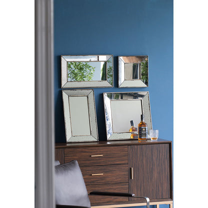 A wooden cabinet against a blue wall displays three Distressed Accent Mirrors, Traditional Style Framed Wall Mirrors for the living room, along with a bottle of whiskey and a glass. A gray cushioned chair is partially visible in the foreground.