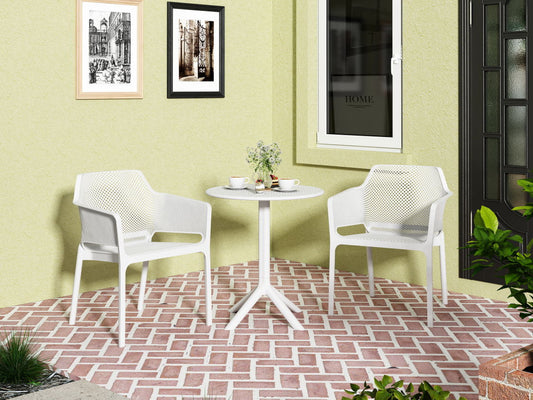 A small patio features the 3 Piece Plastic Arm Chair Bistro Grs Premium Ocean Plastic set—two white chairs and a round table on a red and white herringbone floor, with cups, plates, a vase on the table, and framed pictures on a yellow wall.