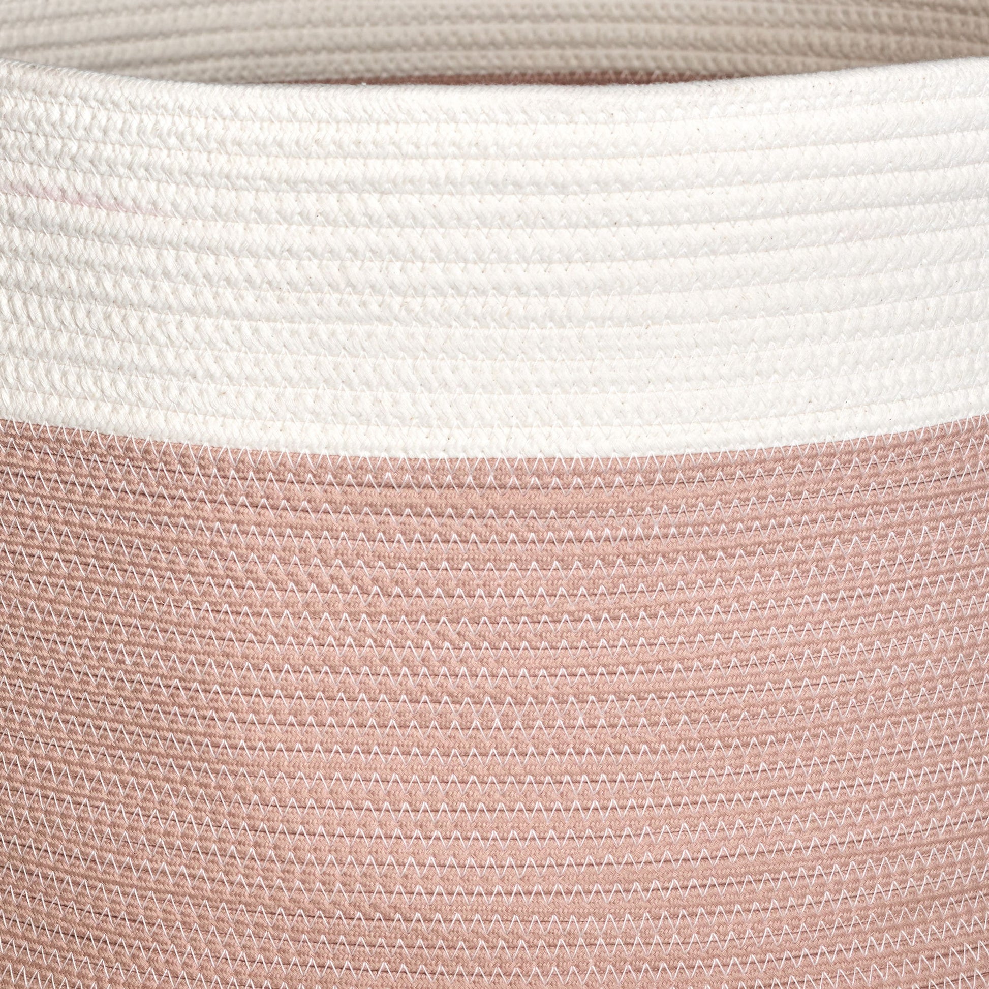 Close-up of the Francis - Cotton Round Laundry and Storage Basket, featuring a textured zigzag pattern. The upper part is white, while the lower section is muted pink, crafted from tightly stitched cotton for durability and style.