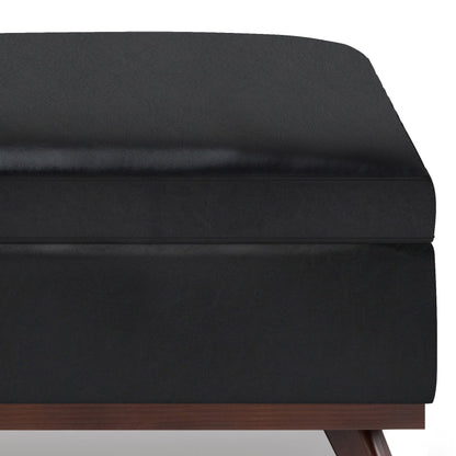 Close-up of the corner of the Owen Multifunctional Square Coffee Table Storage Ottoman with a black cushioned top and wooden base, shown against a white background.