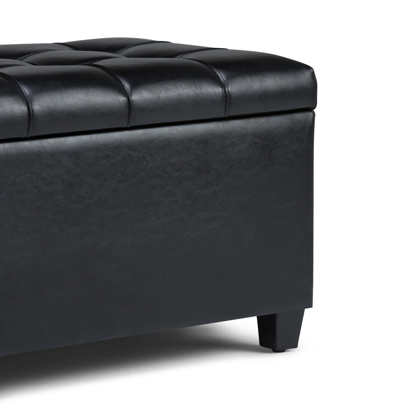 Close-up of the Sienna Upholstered Storage Ottoman Bench in black tufted leather with short legs, showing the corner and top cushion against a plain white background.