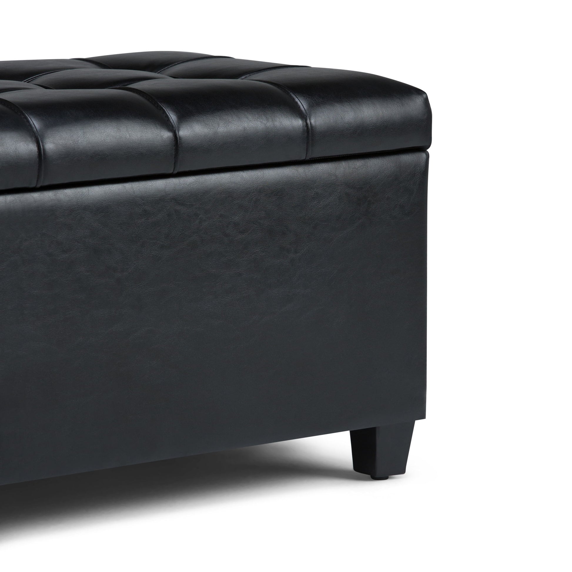 Close-up of the Sienna Upholstered Storage Ottoman Bench in black tufted leather with short legs, showing the corner and top cushion against a plain white background.