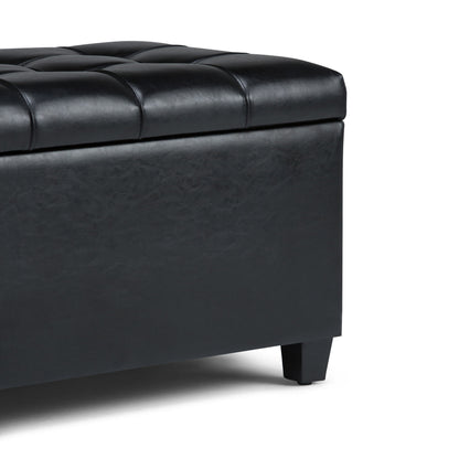 Close-up of the Sienna Upholstered Storage Ottoman Bench in black tufted leather with short legs, showing the corner and top cushion against a plain white background.