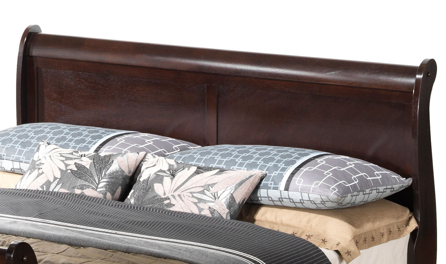 The Panel Sleigh Bed features a dark wood headboard, two blue geometric pillows, two floral pillows, beige sheets, and a dark gray blanket for a stylish and neatly made look.