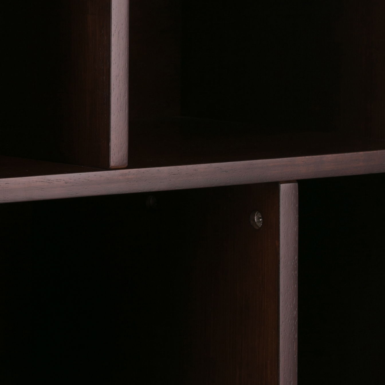 Close-up of the corner of the Draper - Mid Century Wide Bookcase And Storage Unit, highlighting intersecting dark wood panels, a smooth finish, and a visible side screw.