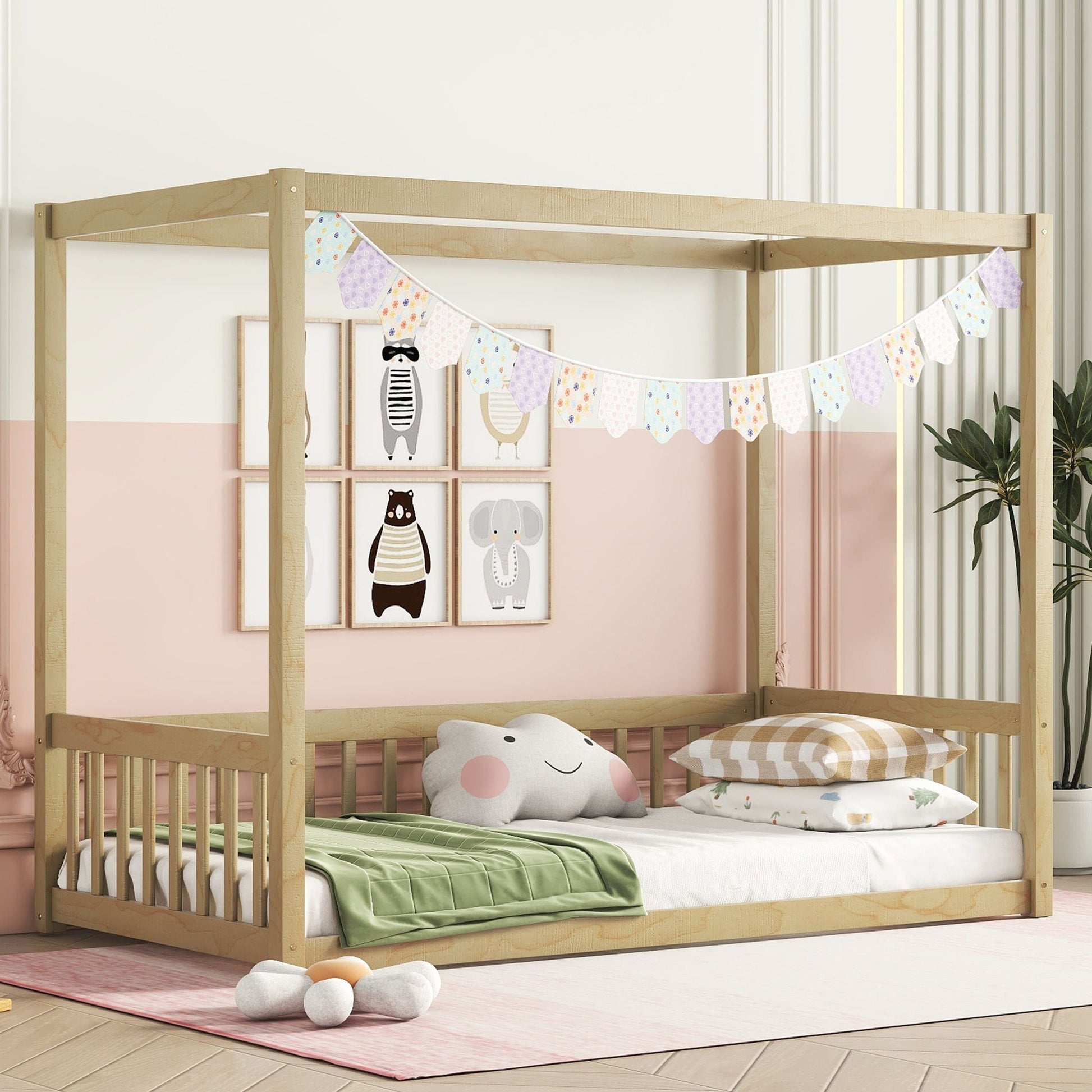 A cozy kids' room features the Canopy Frame Floor Bed With Fence, playful pillows, animal wall art, colorful bunting, a green blanket, and a potted plant against pink and white walls.