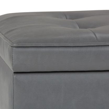 Close-up of the Cosmopolitan Storage Ottoman Bench with open bottom, showing gray tufted faux leather upholstery, visible stitching, padded corner, and part of the top cushion.