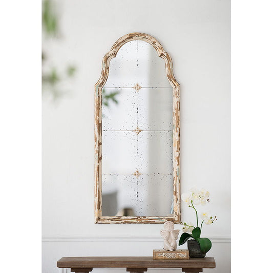 A Large & Framed Wall Mirror, Arched With a Decorative Window Look in cream hangs above a console table, which holds a small statue, a book, and a white orchid in a black pot.