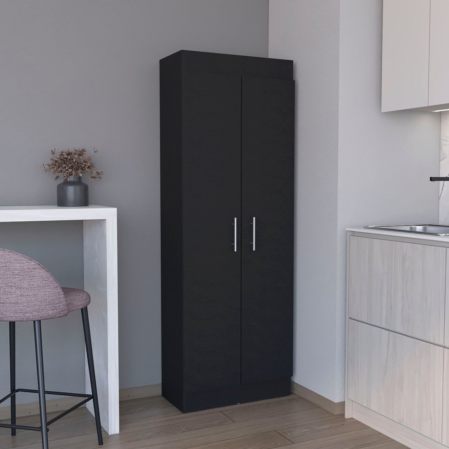 The Clinton Pantry Cabinet Kitchen Storage in black with two doors and silver handles stands by a white counter with a dried flower vase and a purple stool in the modern kitchen.