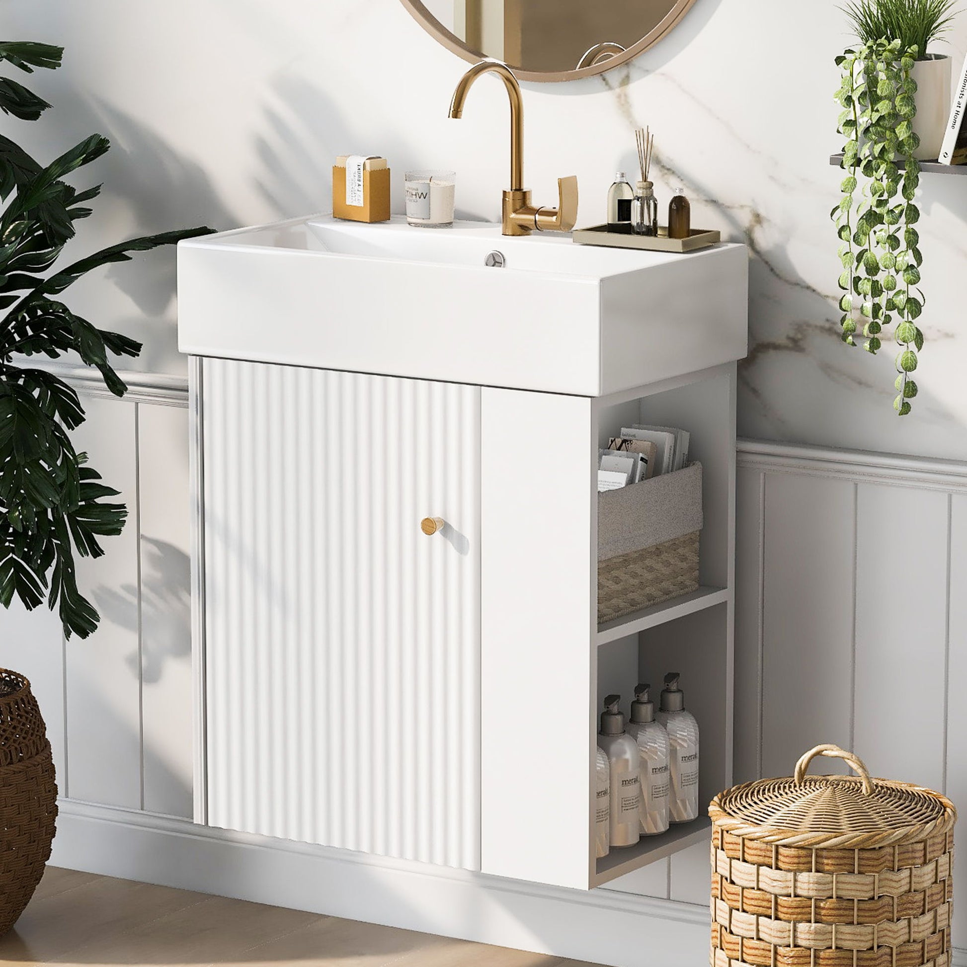 The Modern Floating Bathroom Vanity With Ceramic Basin, ideal for small bathrooms, features a white sink, gold faucet, and open shelves for baskets and bottles. A round mirror hangs above, with green plants nearby and sunlight streaming in.