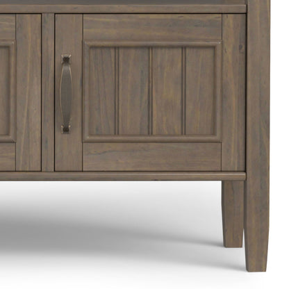 Close-up of the lower section of the Lev Console Table in smoky brown finish, featuring panel detailing, a handle on one door, and tapered legs, set against a plain white background.