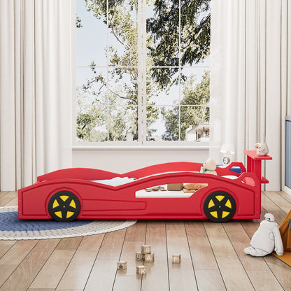A child’s bedroom featuring the Wooden Race Car Bed, Car Shaped Platform Twin Bed With Wheels For Teens, surrounded by toys and stuffed animals, wooden alphabet blocks on a round rug, and large windows with white curtains showing trees.