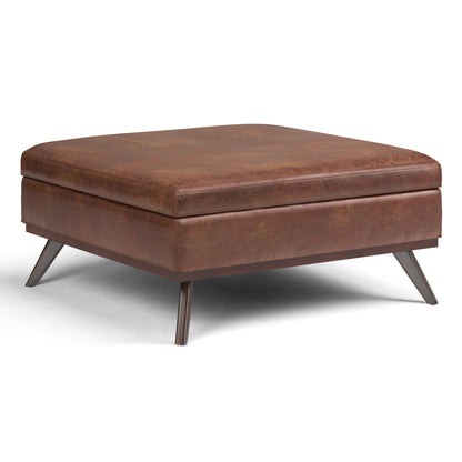 The Owen Multifunctional Square Coffee Table Storage Ottoman features a modern design with brown leather upholstery, angled metal legs, and a flat cushioned top, shown on a white background.