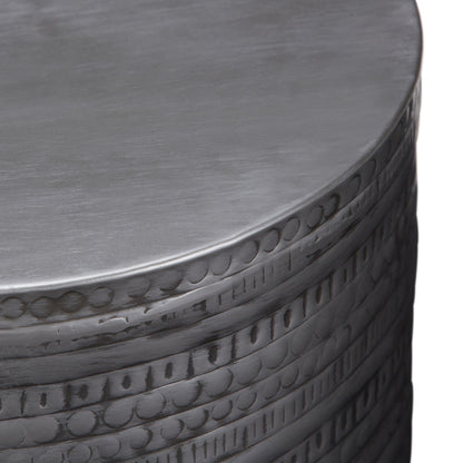 A close-up of the Johnsen - Handcrafted Large Metal Accent Table reveals engraved circular and linear patterns along the side, highlighted by its brushed silver finish.