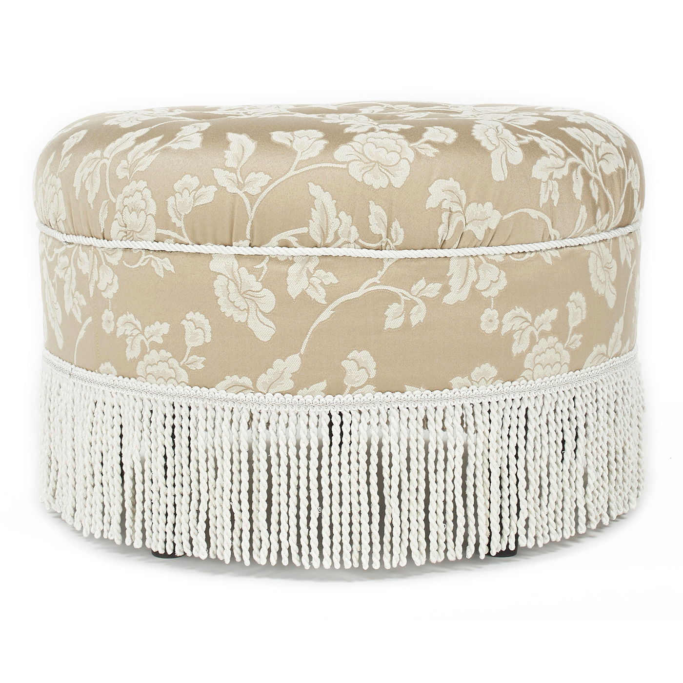 The Yolanda Round Upholstered Accent Ottoman features a beige fabric with white floral patterns, a soft cushioned top, decorative white fringe trim at the base, and offers an elegant vintage look.