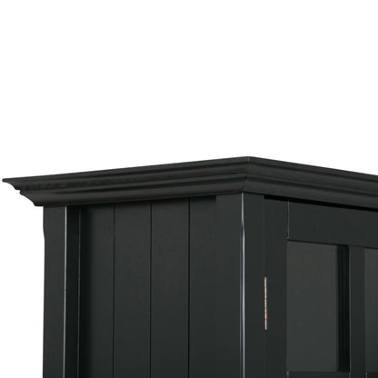 Close-up of the top corner of the Acadian - Medium Storage Cabinet, Handcrafted, featuring black wood with vertical panels and decorative crown molding along the upper edge.