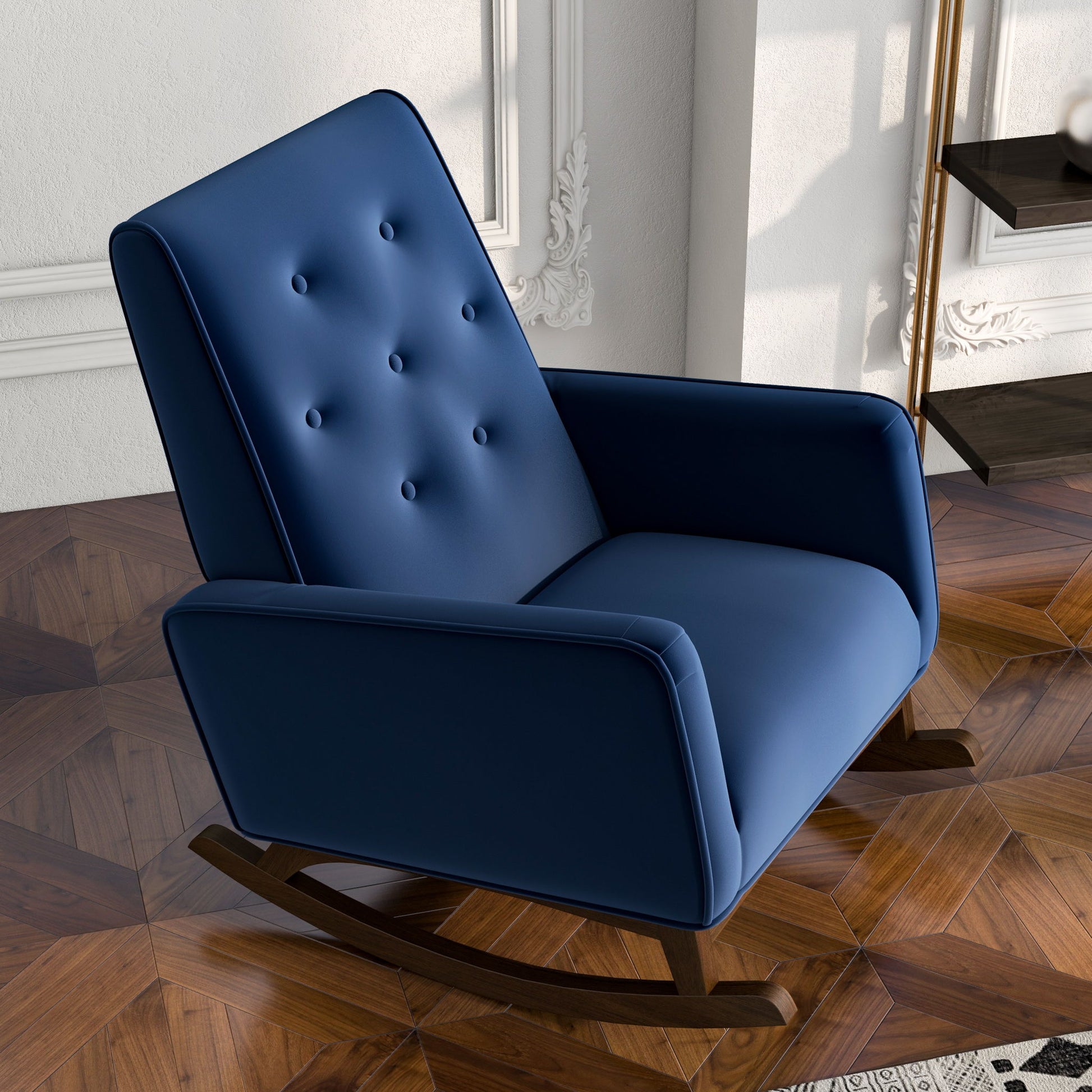 The Demetrius Solid Wood Rocking Chair, featuring modern blue upholstery and a button-tufted backrest, stands on a patterned wooden floor in a stylish room with white paneled walls and decorative molding.