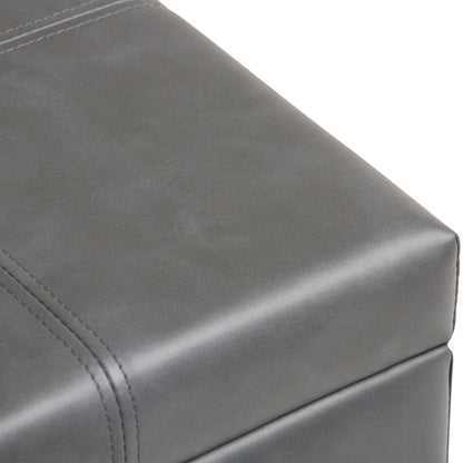 Close-up of the Dover Upholstered Storage Ottoman Bench in gray leather, showcasing visible stitching and a smooth, matte surface.