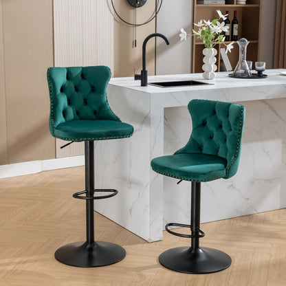A set of two Swivel Velvet Barstools with tufted backs and black metal bases is placed in front of a white marble kitchen island with a black faucet, decorated with a vase of white flowers and kitchenware.