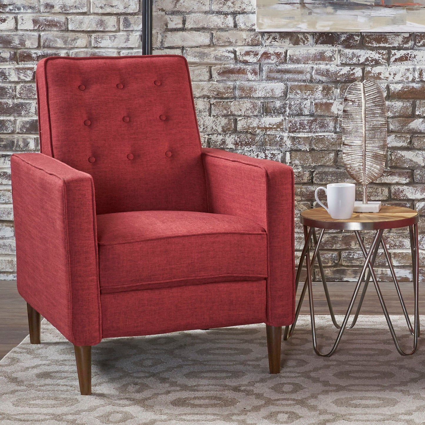 A Mid-Century Modern Recliner With Button Tufted Waffle Stitch sits on a patterned rug by a round side table with a white mug and leaf sculpture, set against a brick wall backdrop.