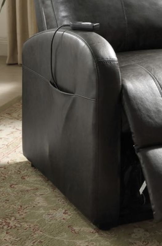 A close-up of the Ricardo - Power Motion Recliner & Lift in brown shows its arm with a remote on top, a side storage pocket, and placement on a subtly patterned light carpet.