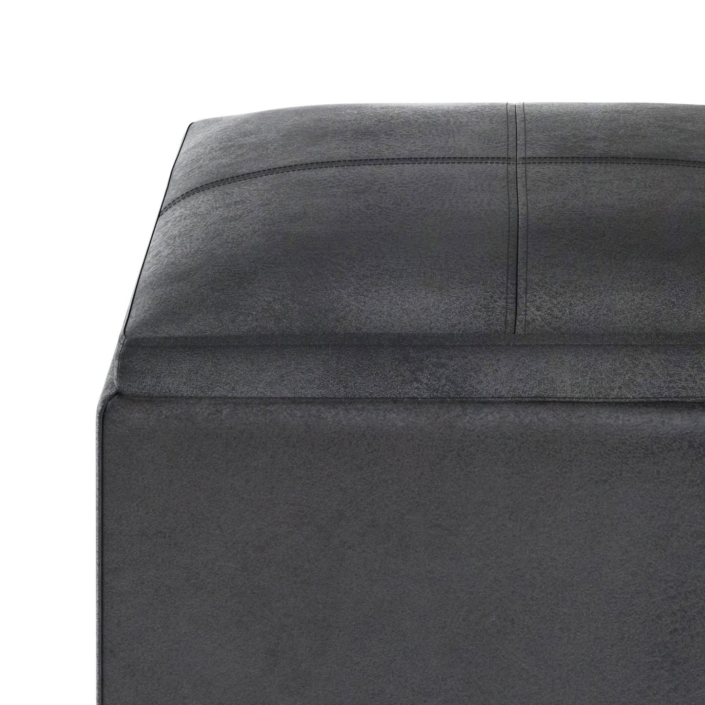 Close-up of the corner of the Rockwood Upholstered Cube Storage Ottoman With Tray in dark gray, showing its square shape and visible stitching on top and sides, set against a white background.