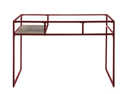 The Yasin - Glass Top Writing Desk features a red metal frame, a clear glass top, and a small wooden shelf on the left. Its modern, open design has no drawers or compartments, perfect for minimalist spaces.