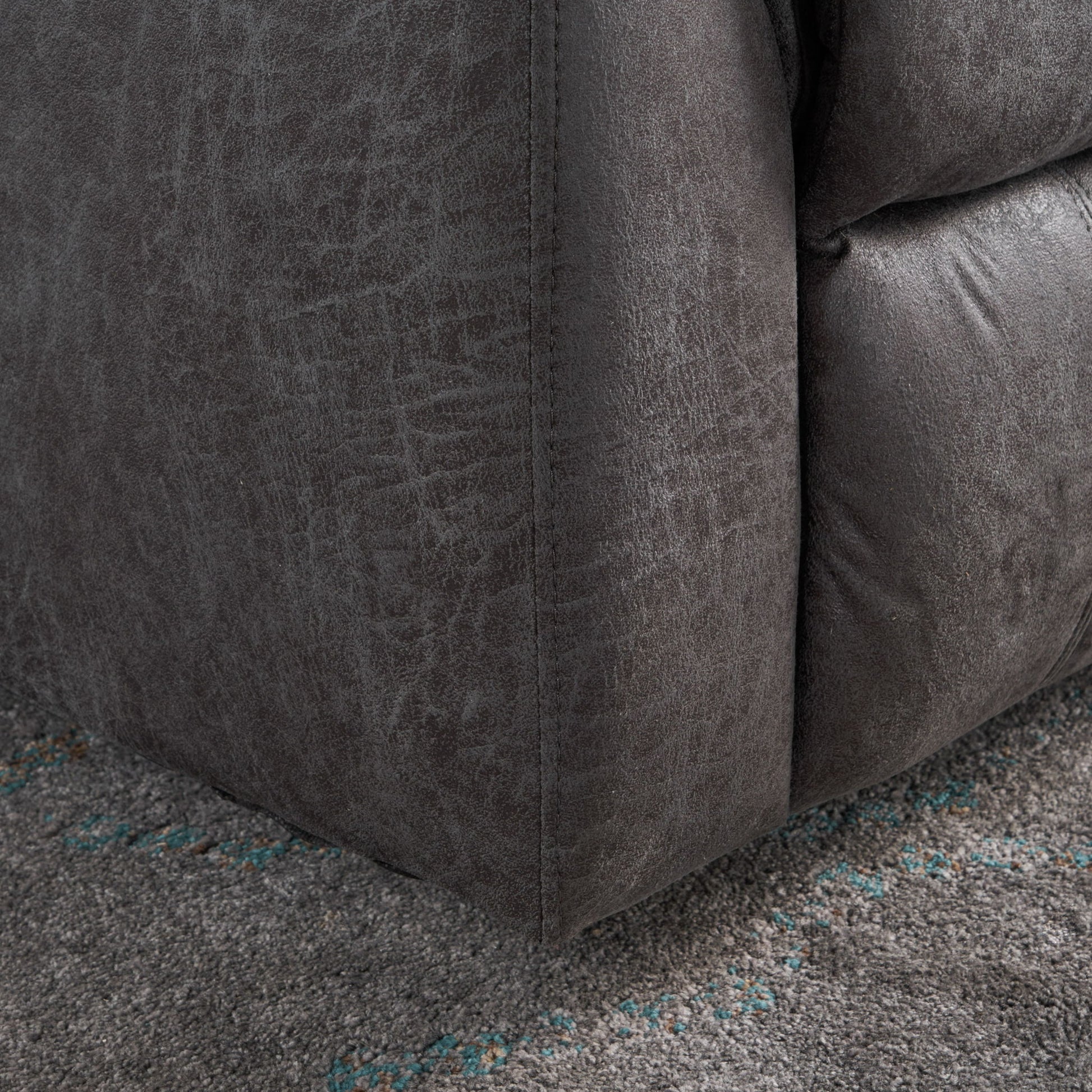 Close-up of the bottom corner of the Contemporary Glider Recliner With Swivel Function, upholstered in dark gray fabric, resting on a textured gray carpet with subtle blue accents.