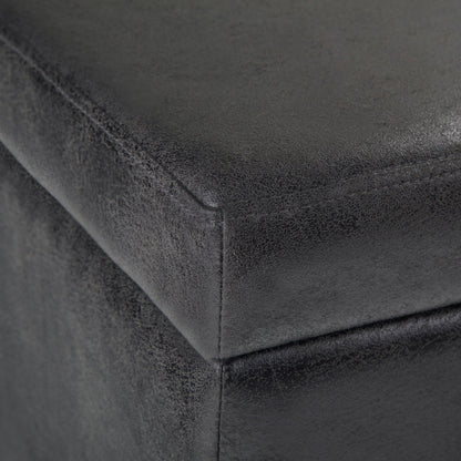 Close-up of the Avalon Storage Ottoman Bench in Distressed Black, highlighting its textured faux leather upholstery, detailed stitching, and material grain.