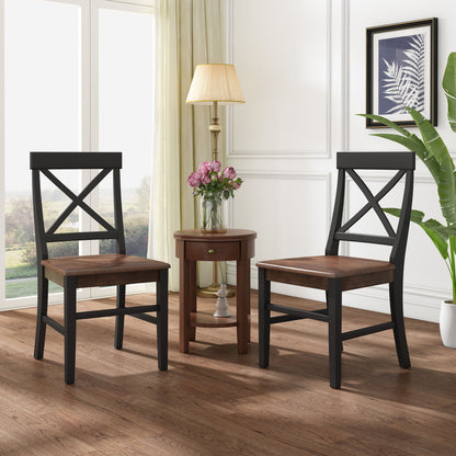 Two Plethora Dining Chairs with X-shaped backs and dark frames sit by a small round side table topped with a lamp and vase. Large windows, light curtains, framed art, and a tall plant add to the cozy atmosphere.