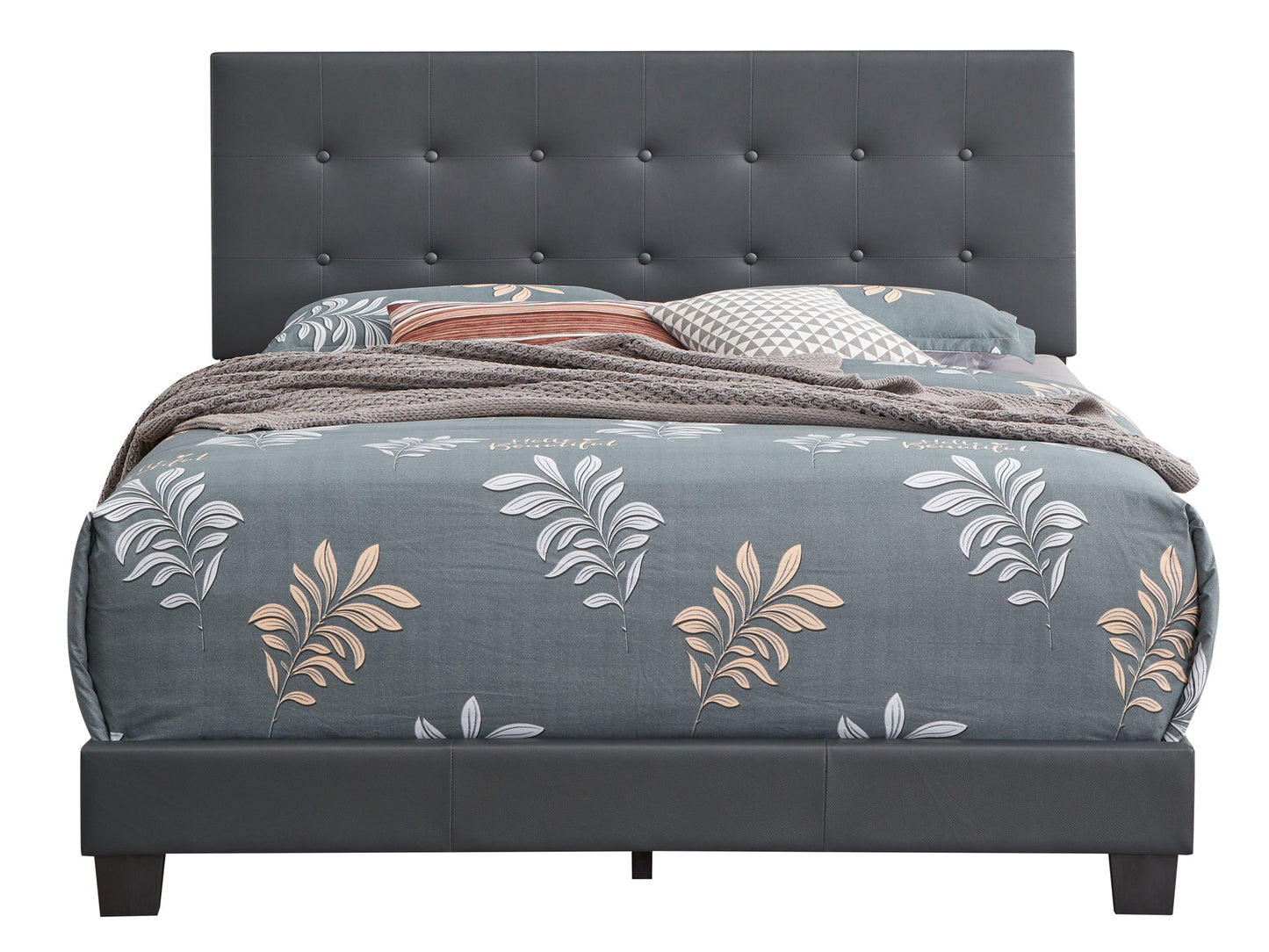 The Caldwell Bed features a dark gray tufted headboard and frame, styled with beige and white leaf-patterned bedding, gray and brown pillows, and a textured blanket.