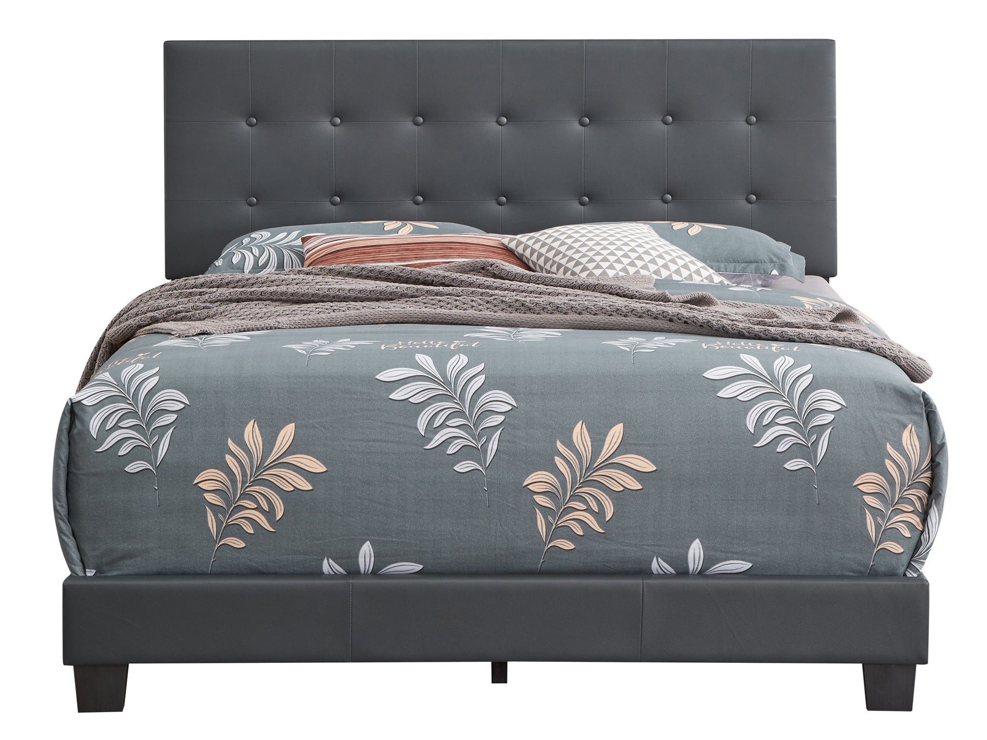 The Caldwell Bed features a dark gray tufted headboard and frame, styled with beige and white leaf-patterned bedding, gray and brown pillows, and a textured blanket.