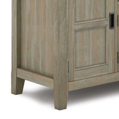 Close-up of the bottom corner of the Burlington - TV Media Stand, showing its light wood finish with visible grain, angled legs, and detailed paneling on the door.