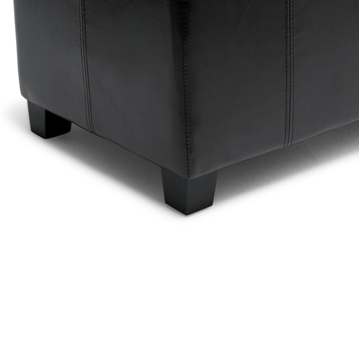 Close-up of the bottom corner of the Dover - Upholstered Storage Ottoman Bench in black leather with dark wooden legs, set on a white background.