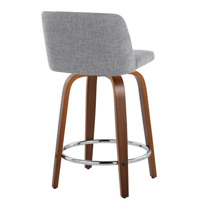 The Toriano Mid Century Modern Counter Stool set offers a gray upholstered seat and backrest with a walnut-finished wooden frame, curved legs, chrome round footrest, and swivel feature, elegantly displayed at an angle from the back.