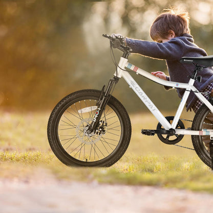 A young child wearing a coat rides the S20101 20" Kids' Bike—a 7-speed mountain bike with front suspension and disc brake—on a grassy path under sunlight. Suitable for boys and girls ages 8-12.
